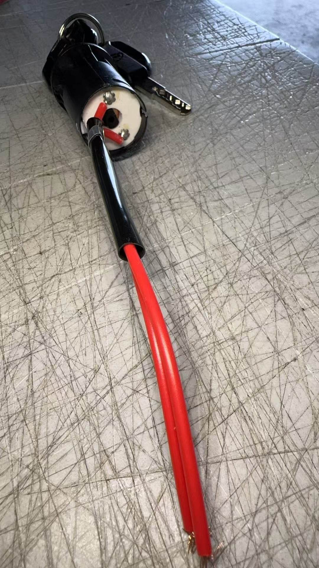 Lock and key set for floor scrubber machine with red wires on scratched metal surface