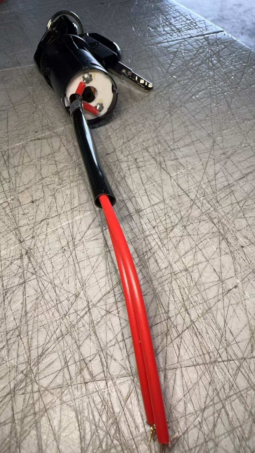 Lock and key set for floor scrubber machines with attached red wires on textured surface