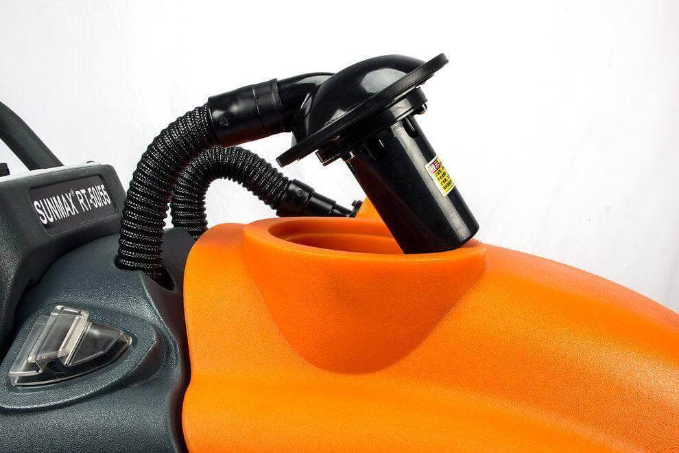 Close-up of RT50 battery powered walk-behind floor scrubber with orange and black components and flexible hose attachment